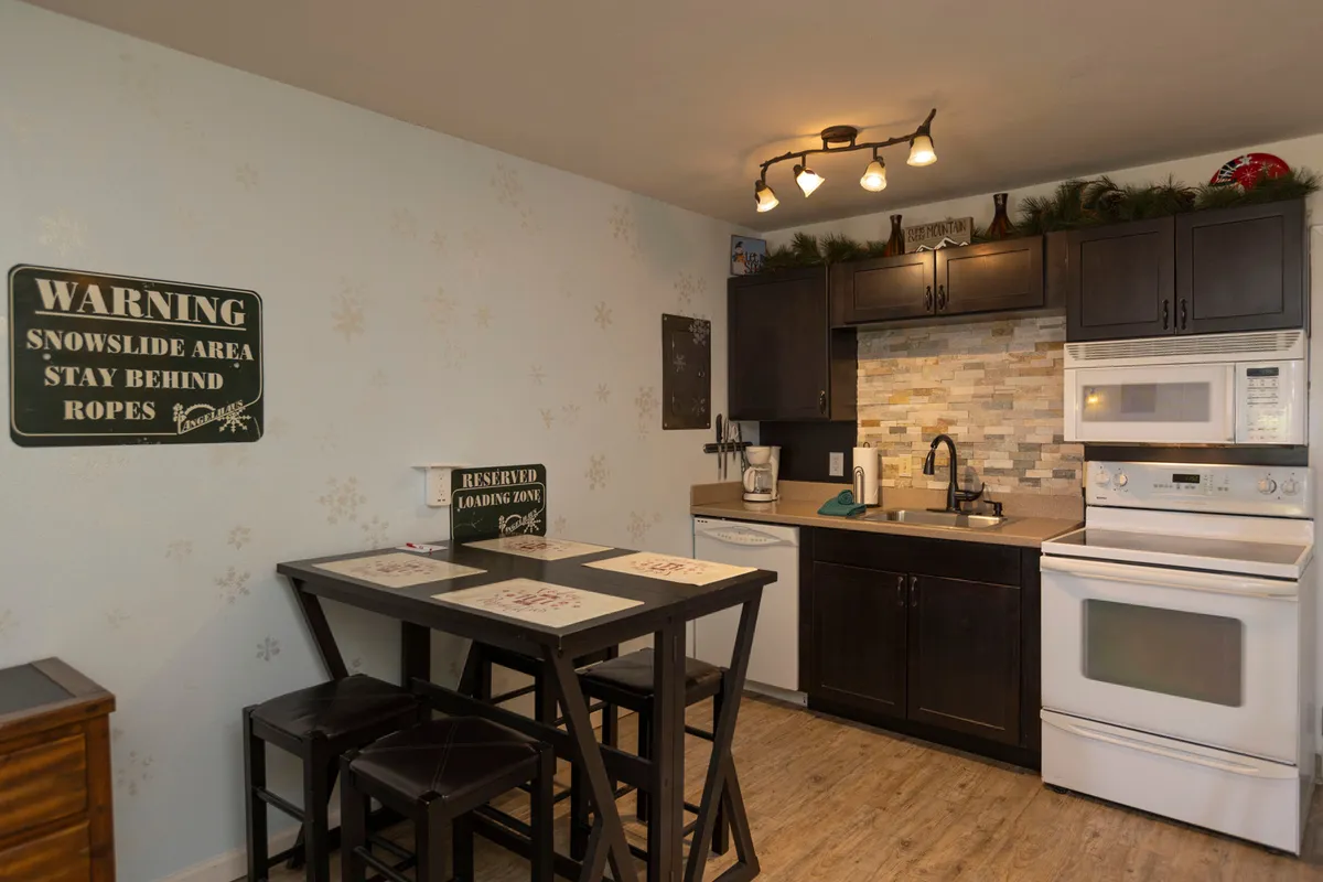 This image focuses on the open-plan kitchen area, with a welcoming counter and stools that invite guests to gather for casual meals or conversation. Decorative accents lend a homey touch, and the seamless connection to the living area is apparent.